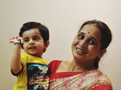 portrait-smiling-woman-with-son-against-wall
